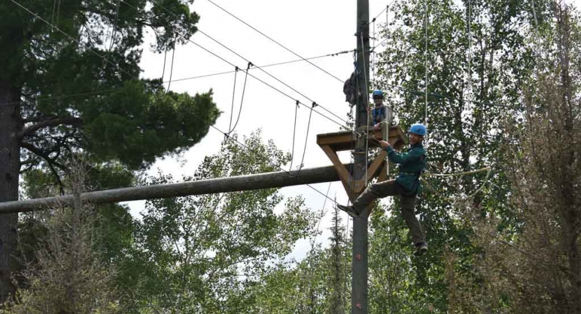 a student balances on ropes while participating in a high ropes course with outward bound